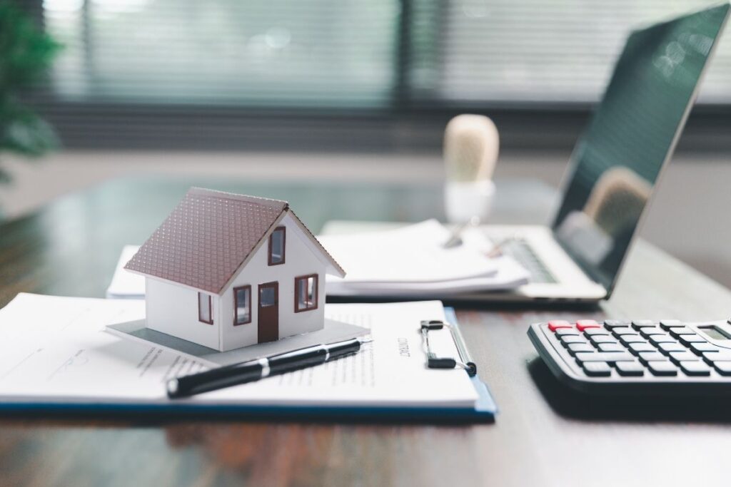 Miniature house and calculator on a desk symbolising strategic finance and property investment planning.