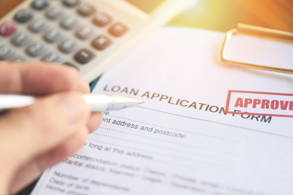 Person filling out a loan application form with a calculator nearby, highlighting finance and borrowing decisions